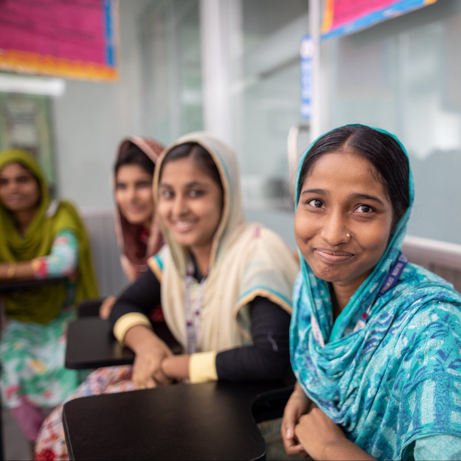 Three women smile while seated for their Empowering Women Workers training
