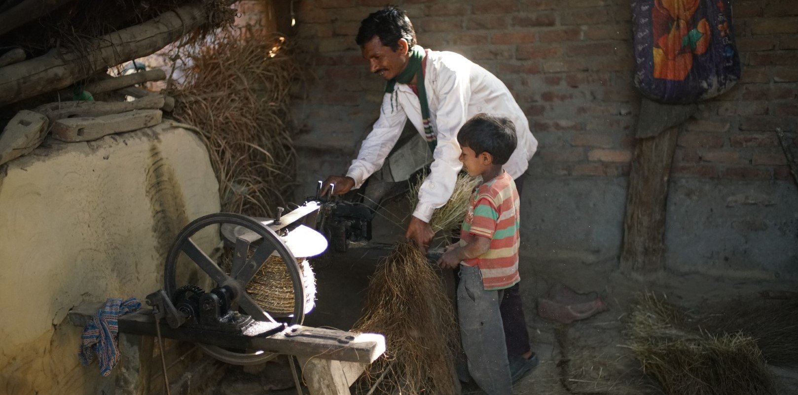 A man and his young boy work on a rope-making machine. 